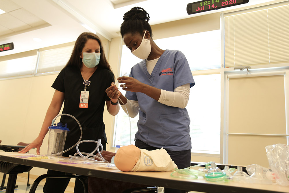 A CNL student learns how to insert a bronchial tube in a pediatric simulation.