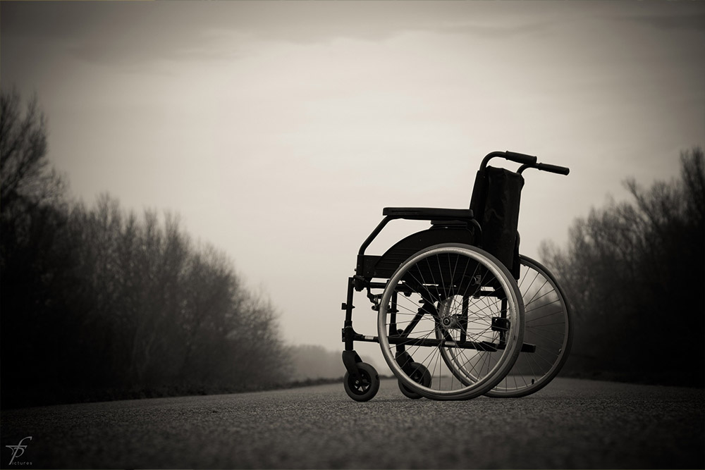 an empty wheelchair silhouetted against a grey sky