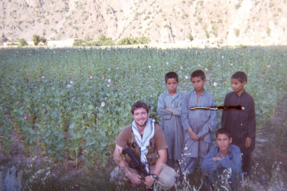 Alumnus and FNP Rhys Williams in a poppy field with Afghani children